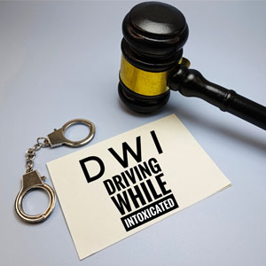Gavel and handcuffs with a card reading DWI Driving While Intoxicated, symbolizing legal consequences
